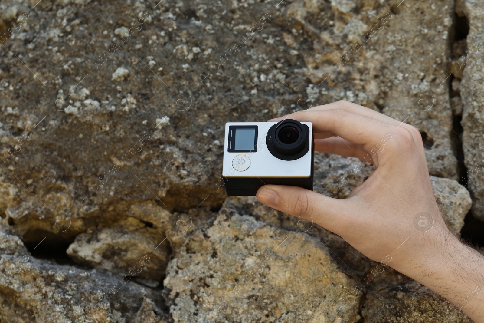 Photo of Man with modern action camera near stones, closeup