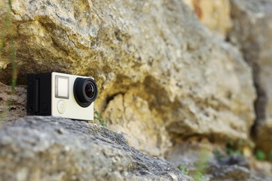 Photo of Modern action camera on stone. Space for text