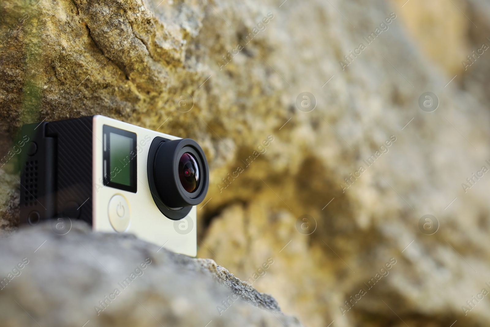 Photo of Modern action camera on stone, closeup. Space for text