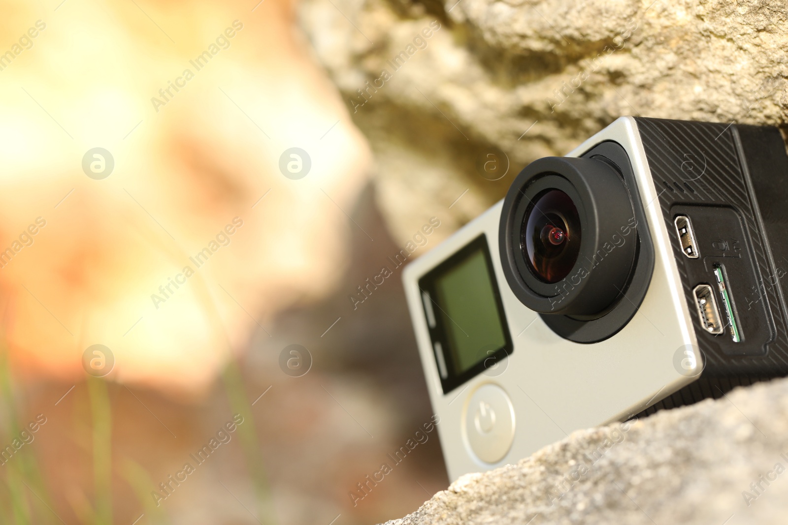 Photo of Modern action camera on stone, closeup. Space for text