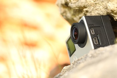 Photo of Modern action camera on stone, low angle view. Space for text