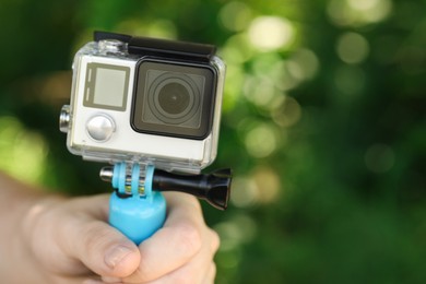 Photo of Man holding monopod with modern action camera outdoors, closeup. Space for text