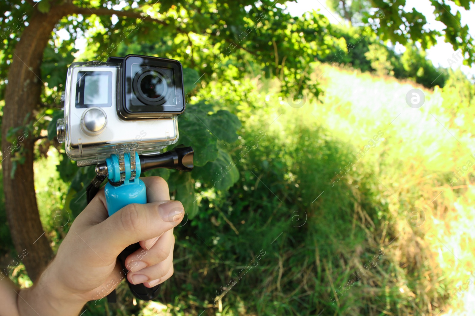 Photo of Man holding monopod with modern action camera outdoors, closeup. Space for text