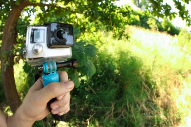 Photo of Man holding monopod with modern action camera outdoors, closeup. Space for text