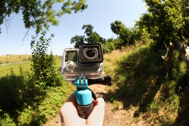 Man holding monopod with modern action camera outdoors, closeup