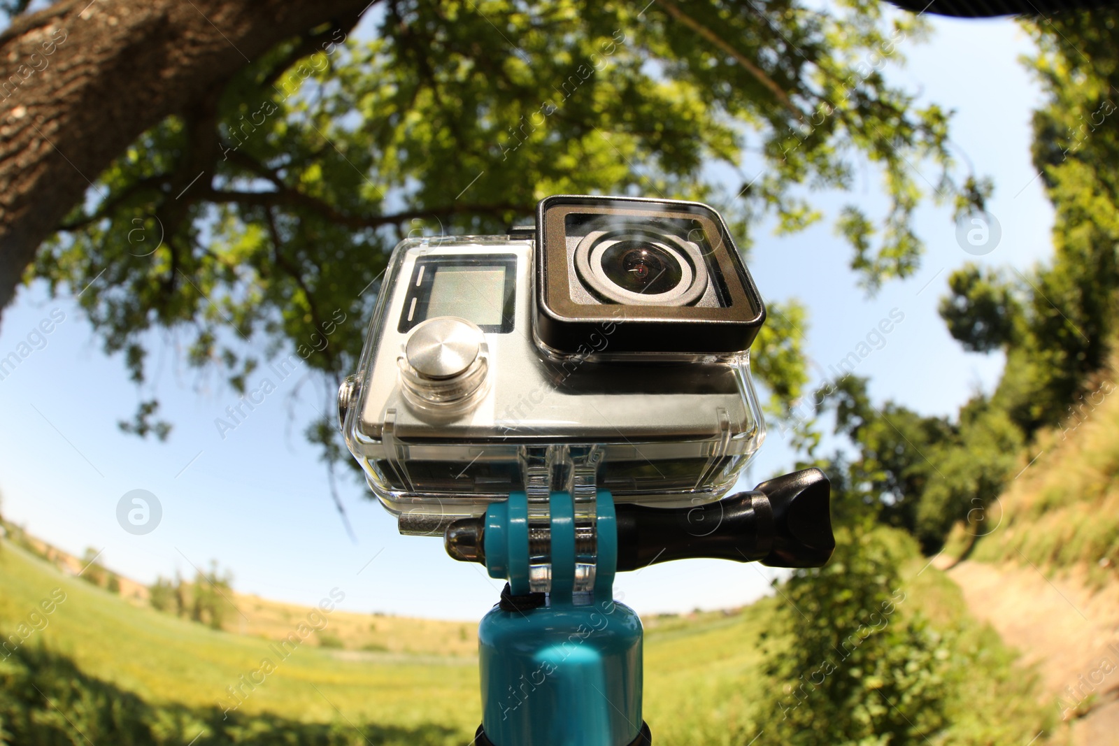 Photo of Modern action camera with monopod outdoors. Fisheye lens effect