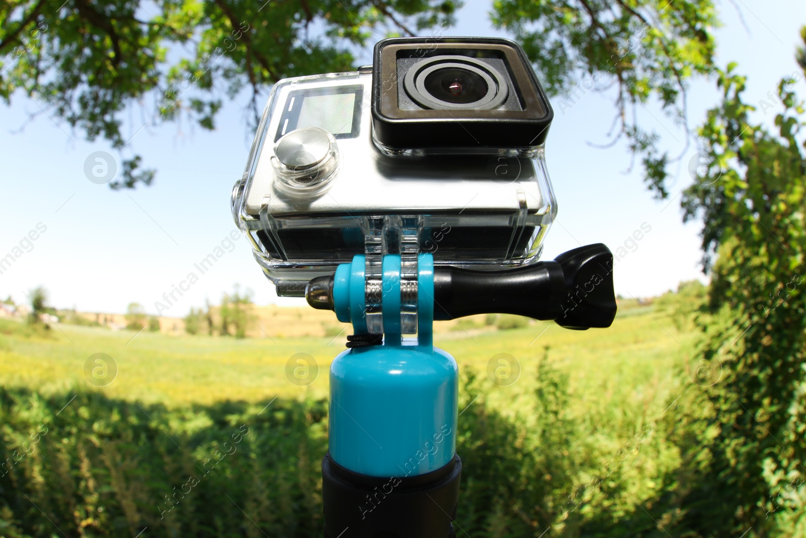 Photo of Modern action camera with monopod outdoors. Fisheye lens effect