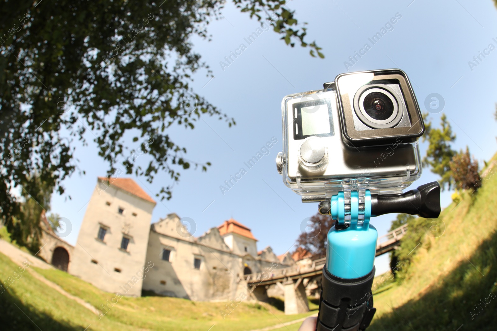 Photo of Modern action camera with monopod outdoors, space for text. Fisheye lens effect