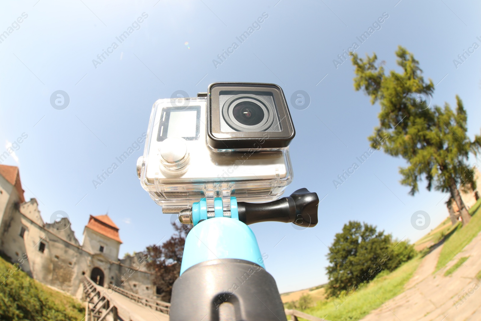 Photo of Modern action camera with monopod outdoors. Fisheye lens effect