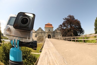 Photo of Modern action camera with monopod outdoors, space for text. Fisheye lens effect