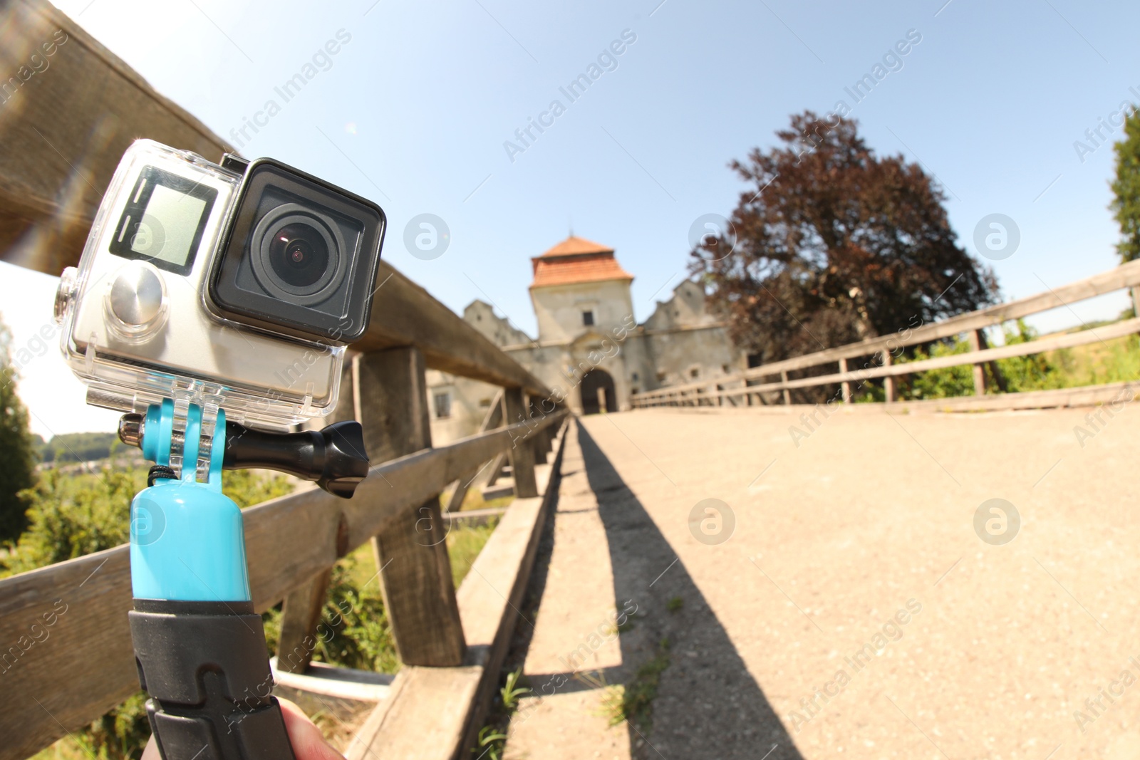 Photo of Modern action camera with monopod outdoors, space for text. Fisheye lens effect