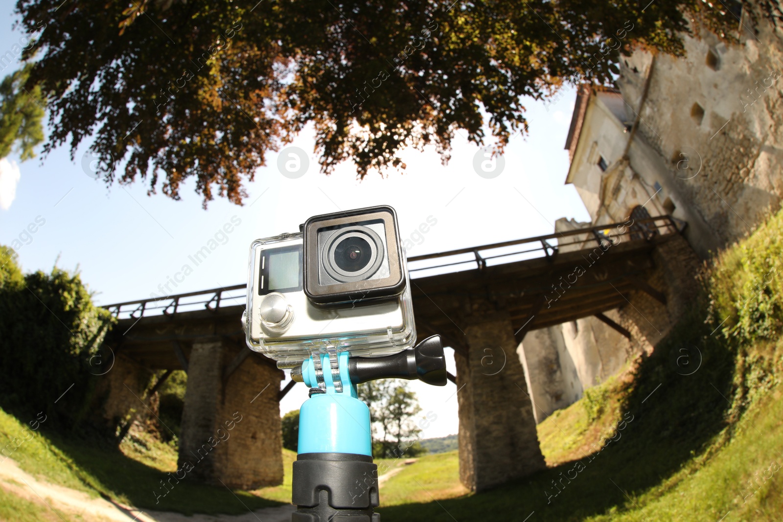 Photo of Modern action camera with monopod outdoors. Fisheye lens effect