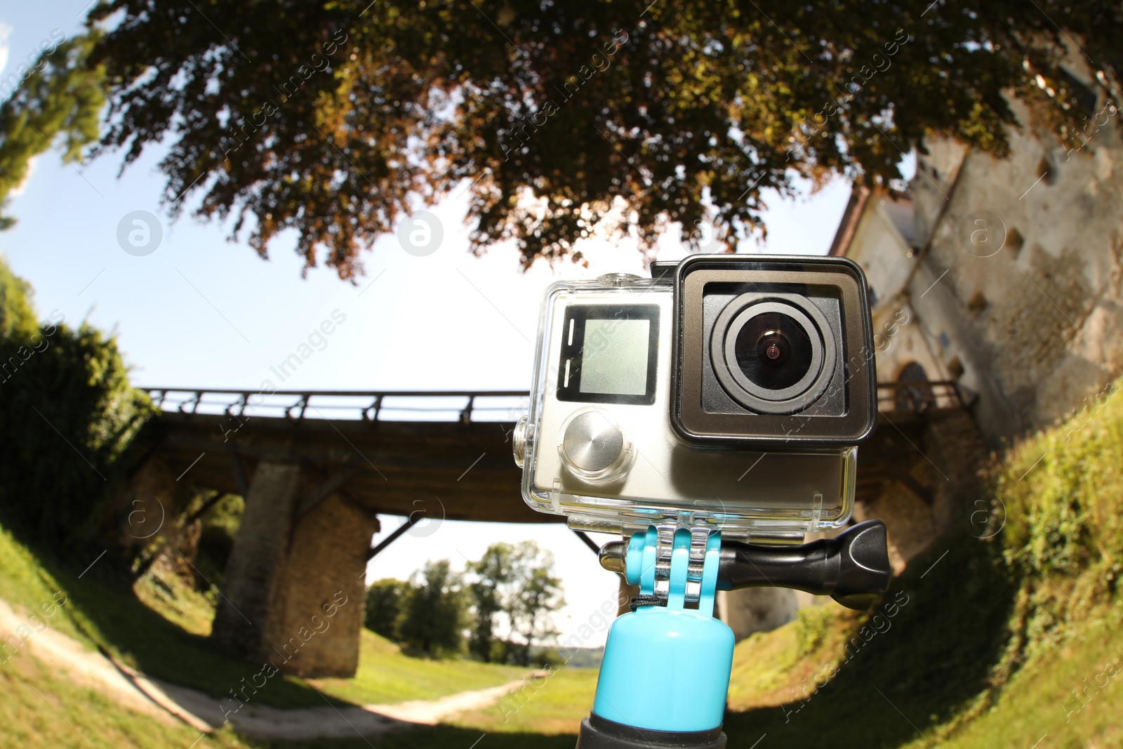 Photo of Modern action camera with monopod outdoors. Fisheye lens effect