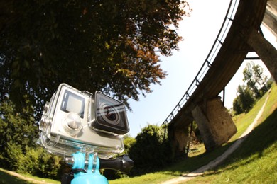 Photo of Modern action camera with monopod outdoors, space for text. Fisheye lens effect