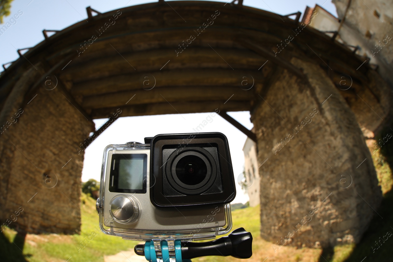 Photo of Modern action camera with monopod outdoors. Fisheye lens effect