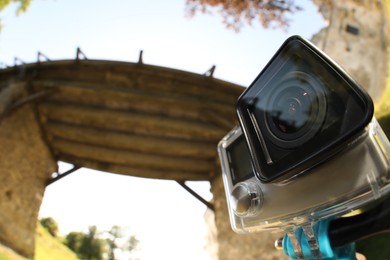 Photo of Modern action camera with monopod outdoors. Fisheye lens effect