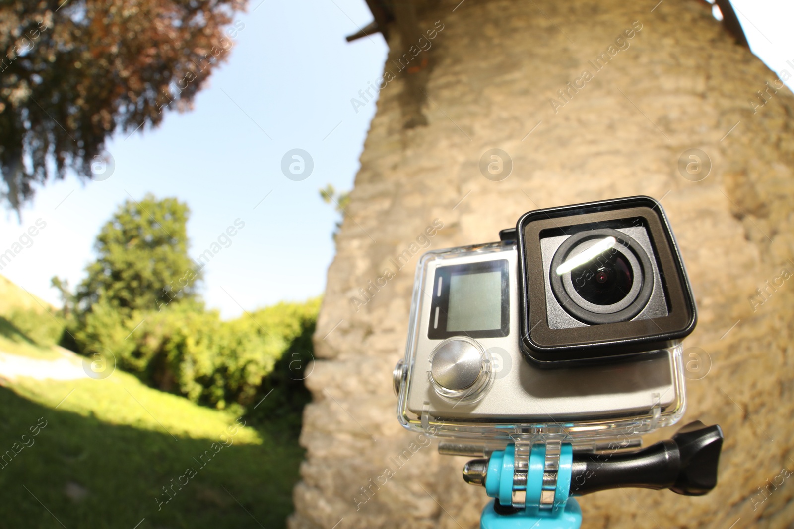 Photo of Modern action camera with monopod outdoors, space for text. Fisheye lens effect