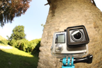 Photo of Modern action camera with monopod outdoors, space for text. Fisheye lens effect