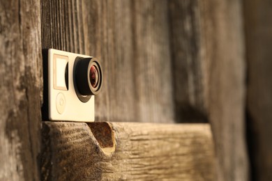 Photo of Modern action camera on wooden surface, closeup. Space for text