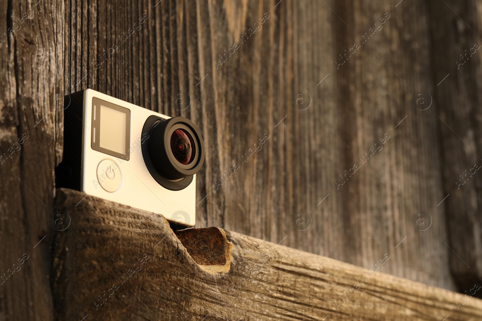 Photo of Modern action camera on wooden surface. Space for text