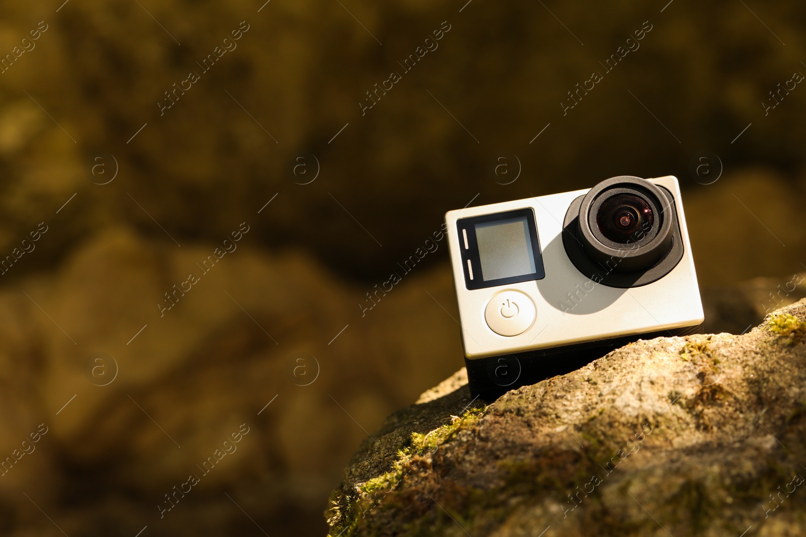 Photo of Modern action camera on stone. Space for text