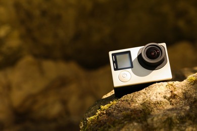 Modern action camera on stone. Space for text