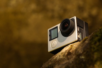 Photo of Modern action camera on stone, closeup. Space for text