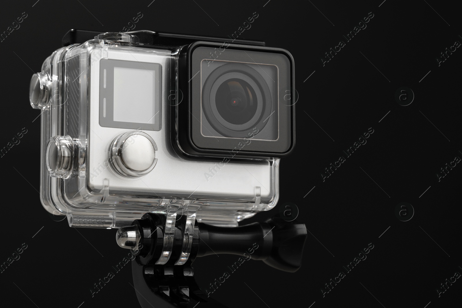 Photo of Modern action camera and mount against black background, closeup