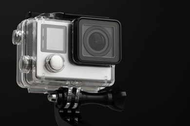 Modern action camera and mount against black background, closeup