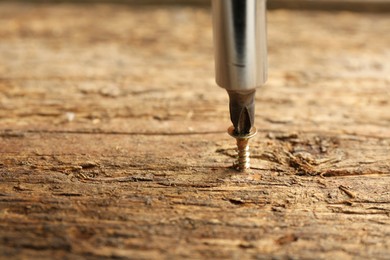 Photo of Screwing screw into wooden surface, closeup. Space for text