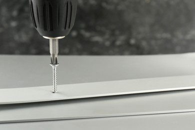 Photo of Screwing screw into white panel at light table, closeup. Space for text