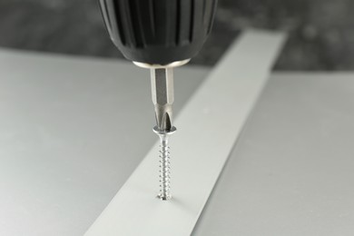 Photo of Screwing screw into white panel at light table, closeup