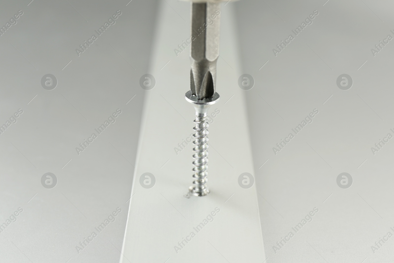 Photo of Screwing screw into white panel at light table, closeup