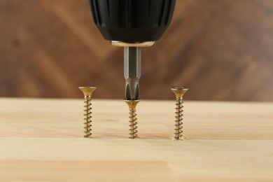 Photo of Screwing screw into wooden plank, closeup view