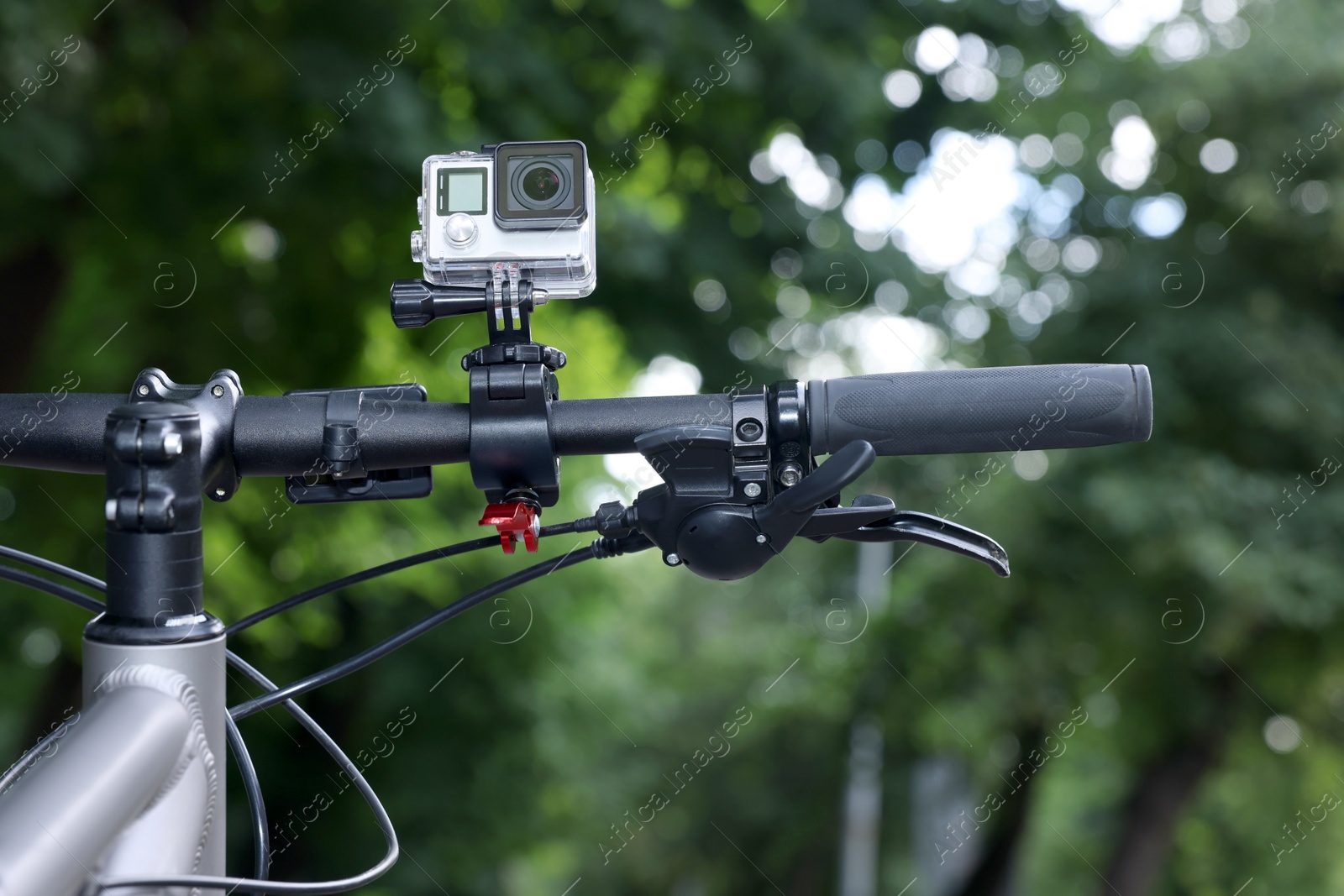 Photo of Modern action camera with mount on bicycle outdoors, closeup