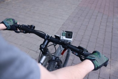 Man riding bicycle with modern action camera outdoors, closeup