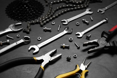 Different bicycle components and tools on dark gray textured background, closeup