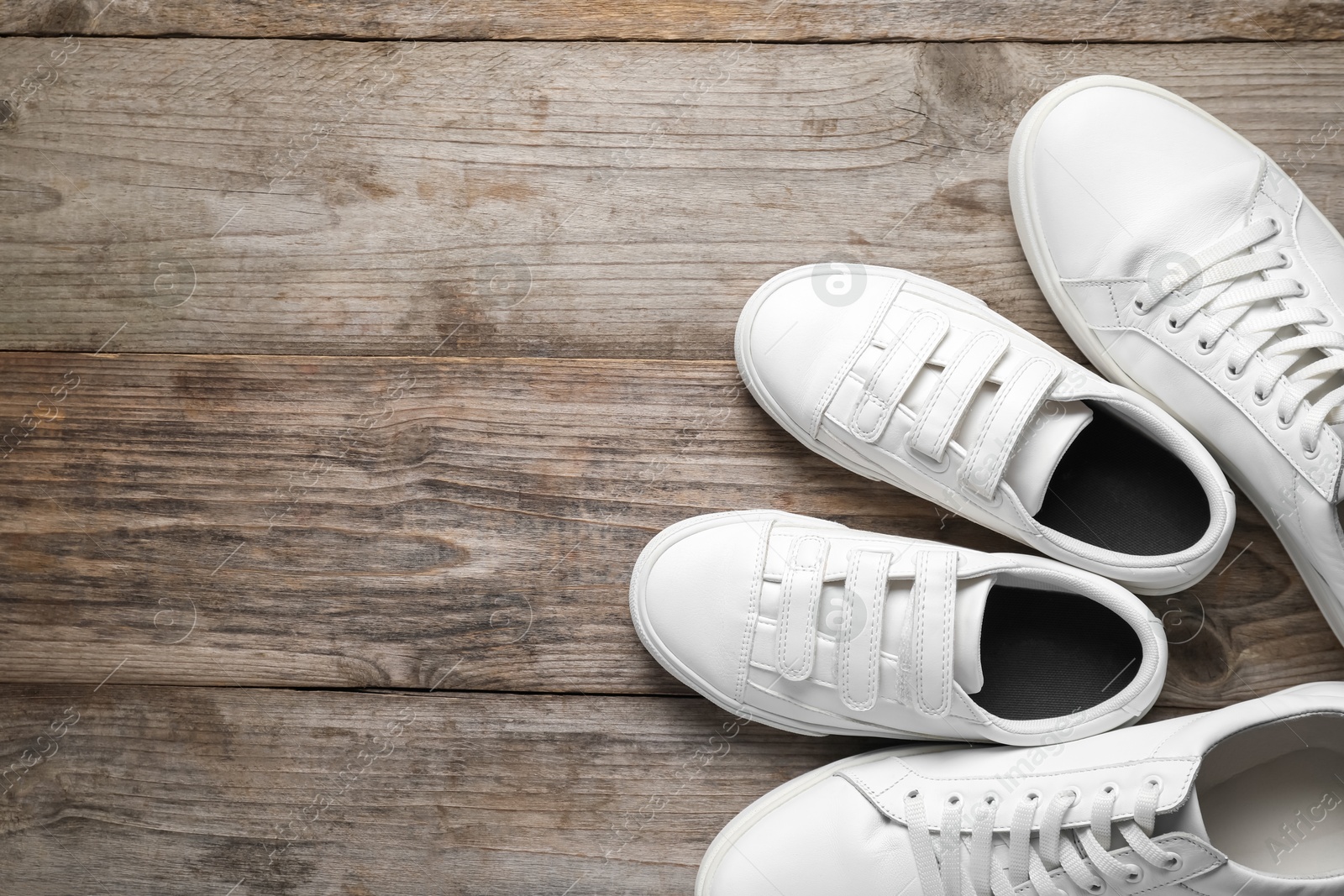 Photo of Big and small shoes on wooden table, top view. Space for text