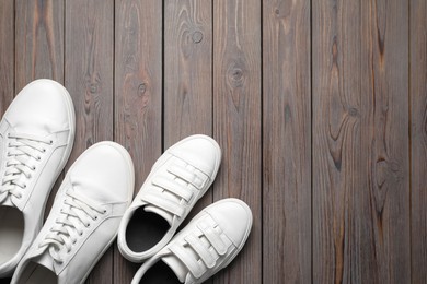 Photo of Big and small shoes on wooden table, top view. Space for text