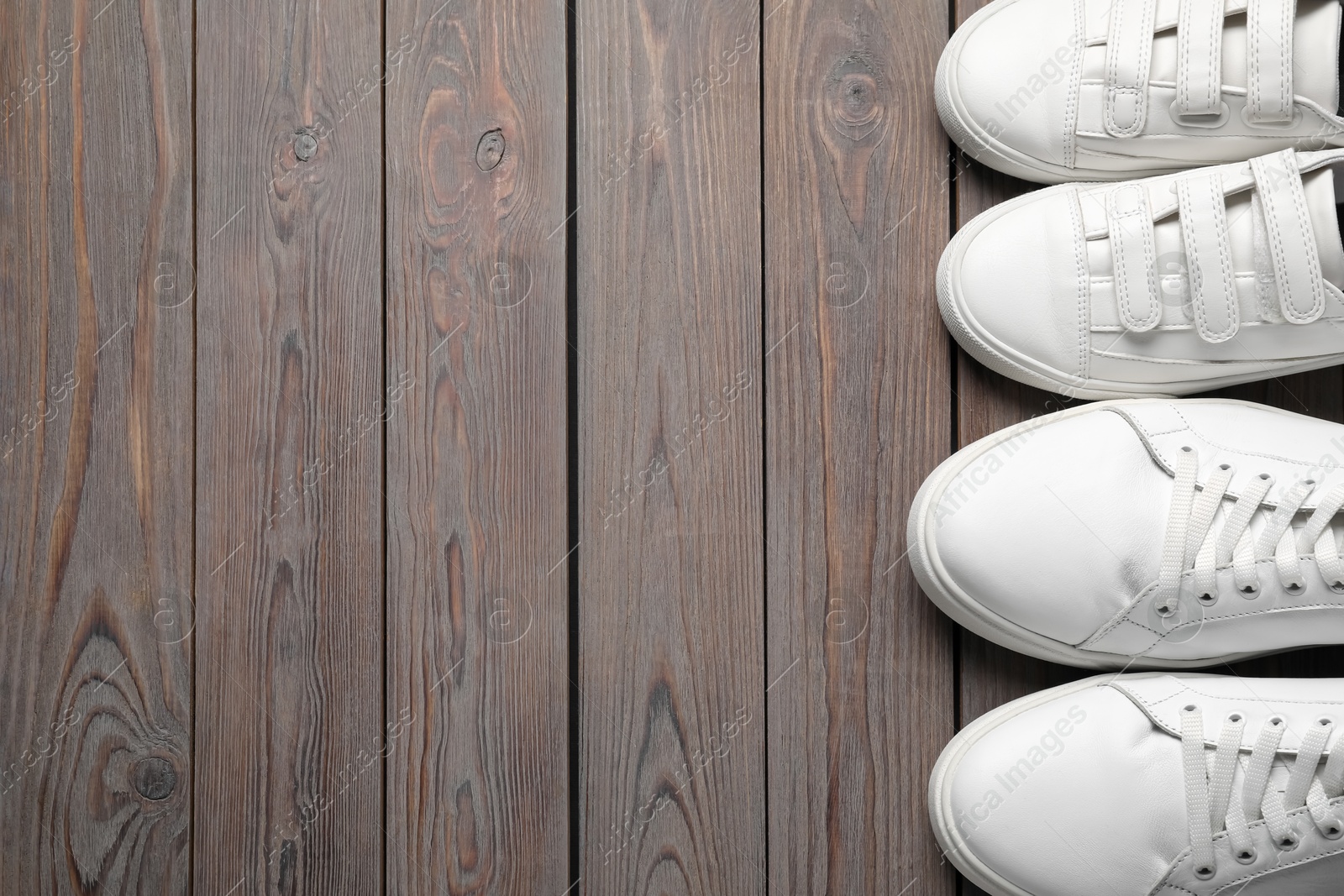 Photo of Big and small shoes on wooden table, top view. Space for text