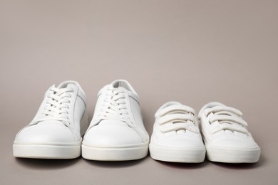 Big and small shoes on grey background