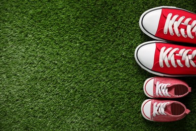 Photo of Big and small shoes on green grass, top view. Space for text