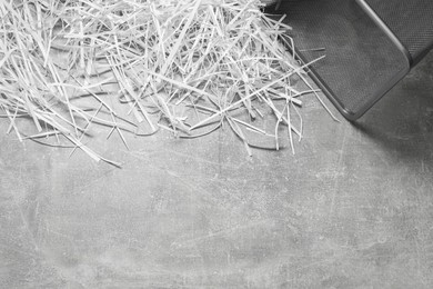 Photo of Shredded paper strips with trash bin on grey textured table, top view. Space for text