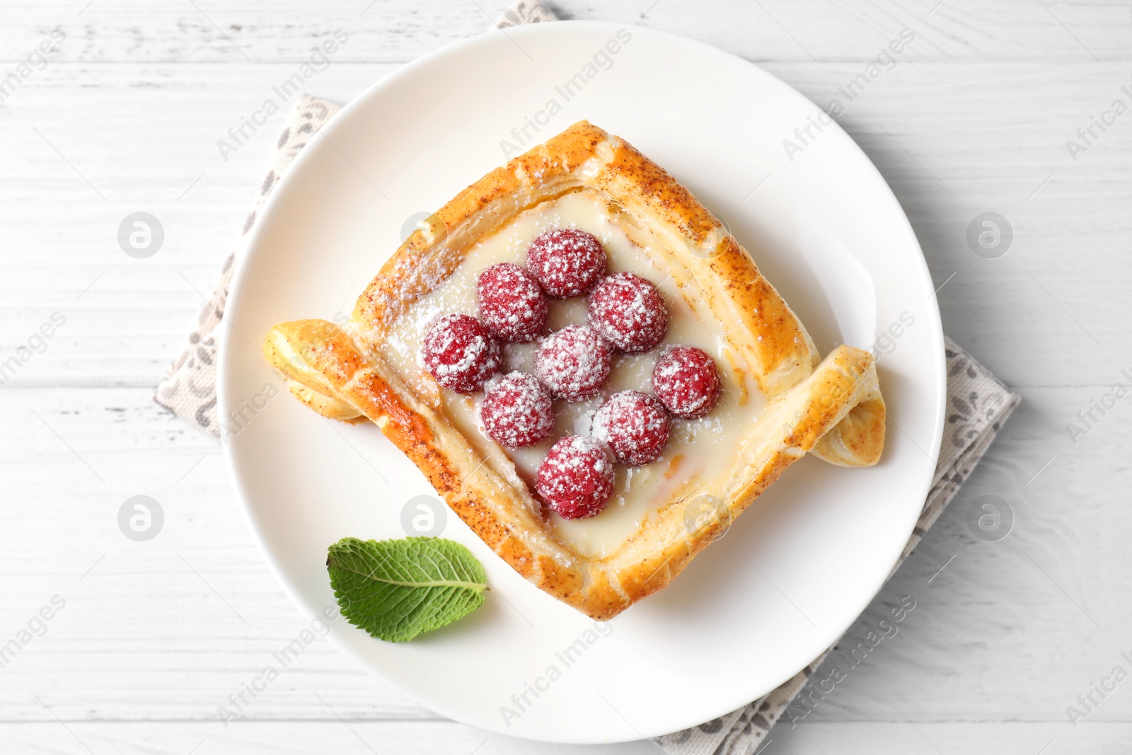 Photo of Tasty puff pastry with raspberries on white wooden table, top view