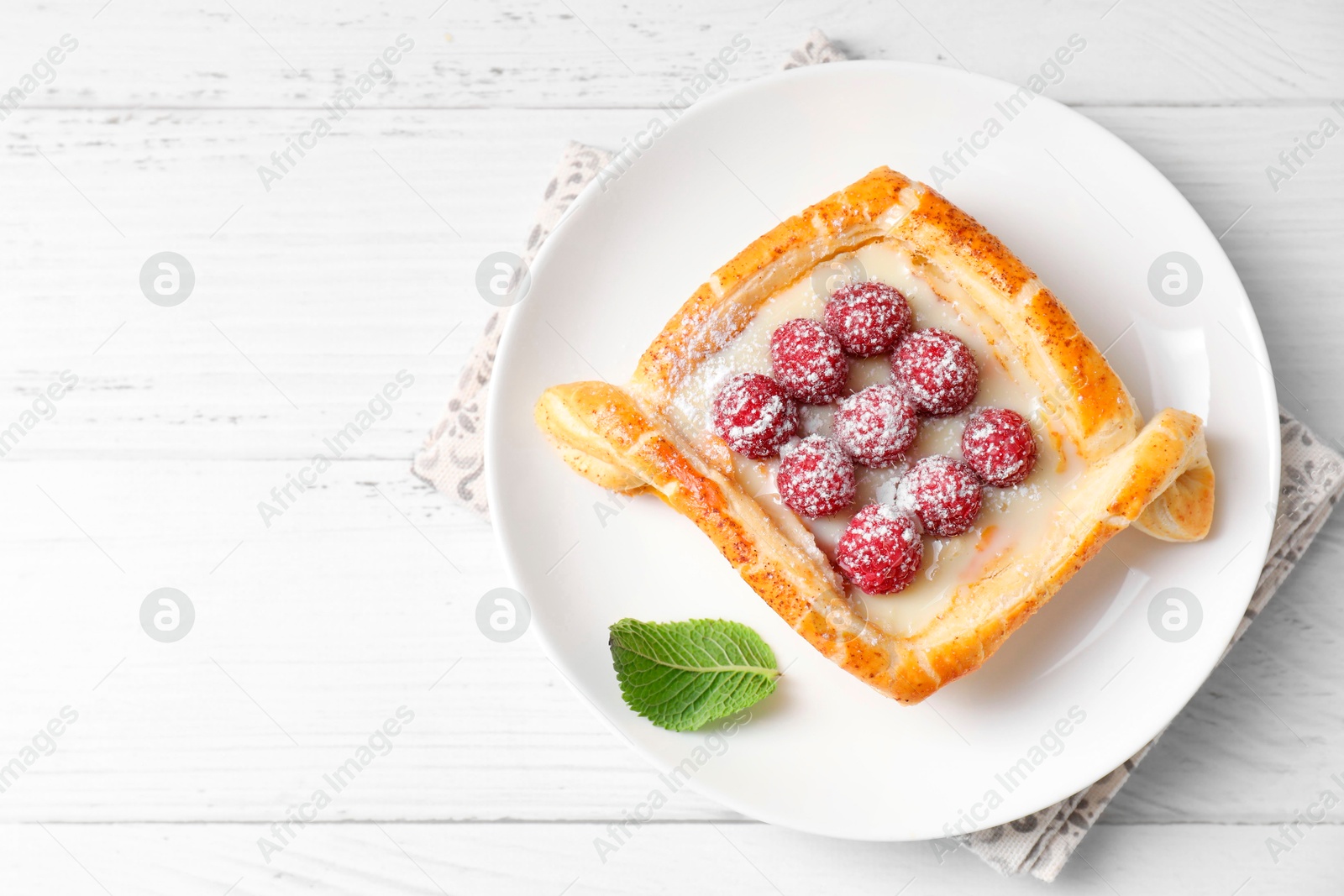 Photo of Tasty puff pastry with raspberries on white wooden table, top view. Space for text