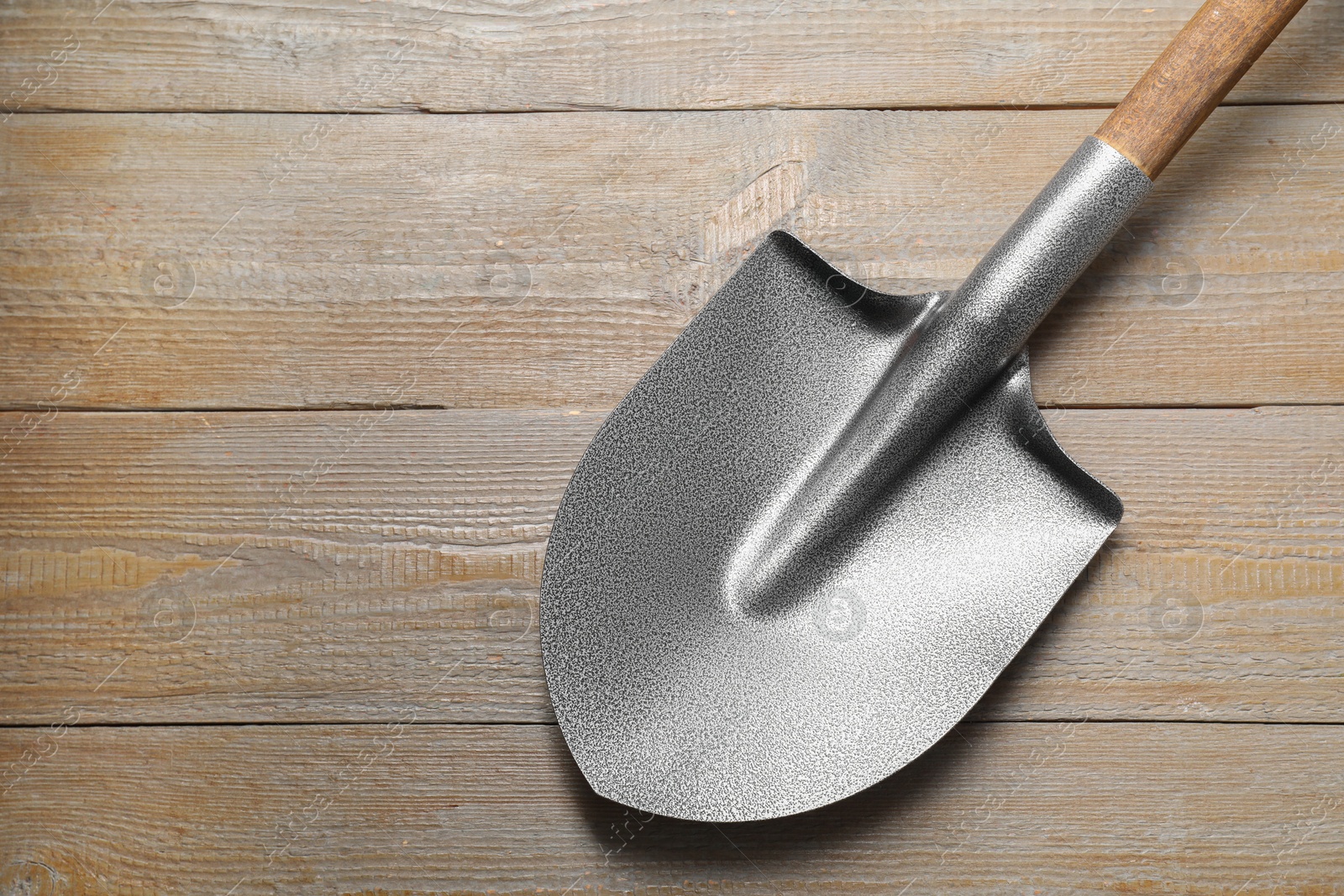 Photo of Metal shovel on wooden table, top view. Space for text