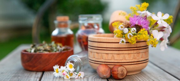 Photo of Different ingredients for tincture, mortar and pestle on wooden bench outdoors