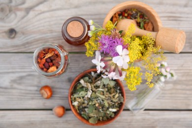 Tincture in bottle, different ingredients, mortar and pestle on wooden table, flat lay