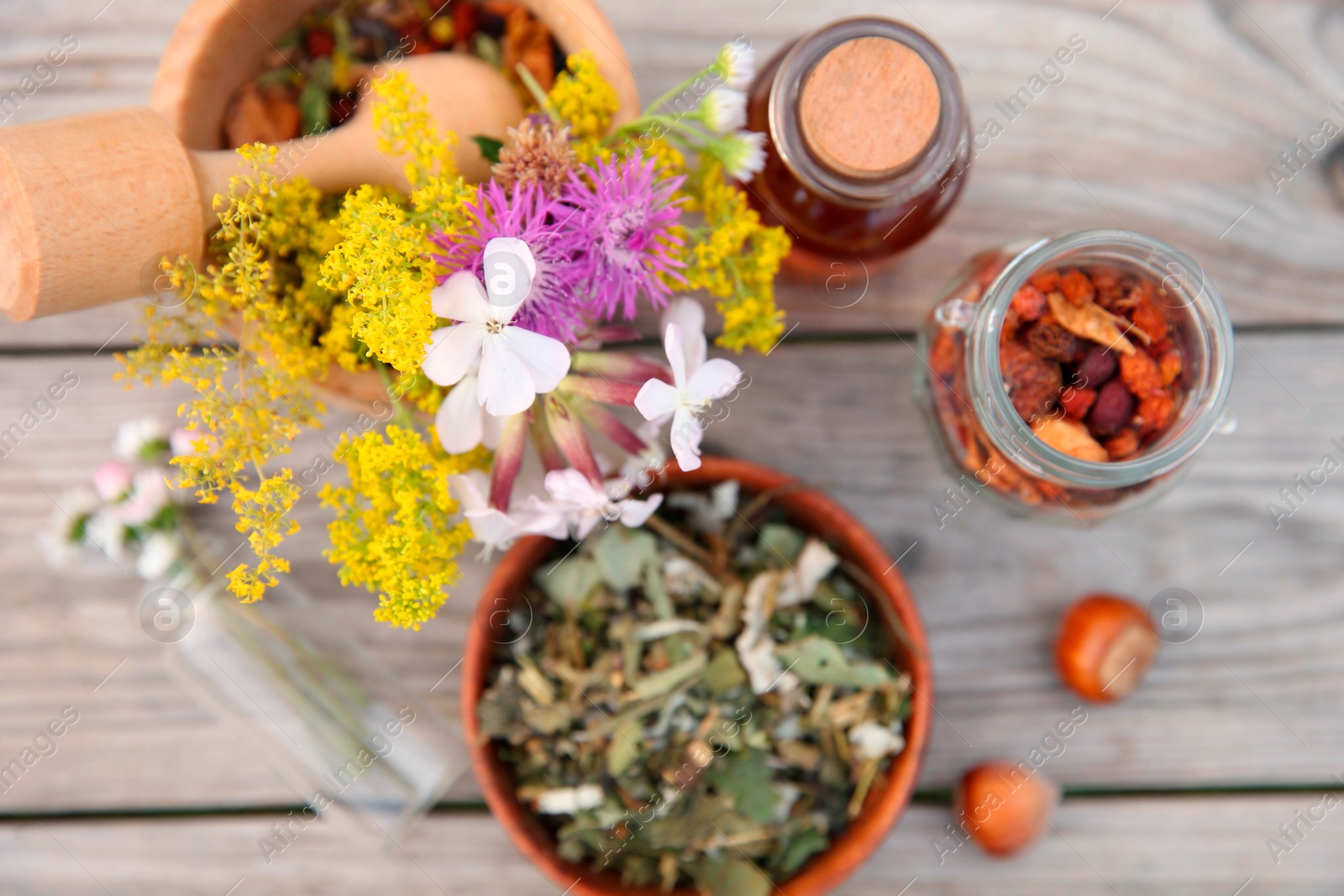 Photo of Tincture in bottle, different ingredients, mortar and pestle on wooden table, flat lay