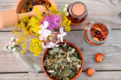 Tincture in bottle, different ingredients, mortar and pestle on wooden table, flat lay